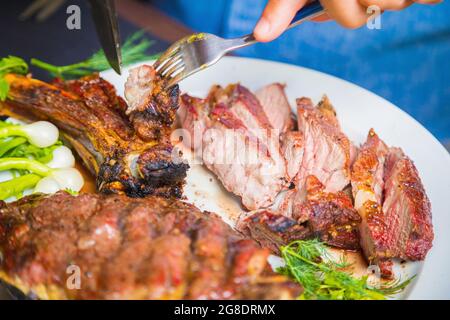 A man cuts cooked fried meat in a plate. Oven-roasted meat for dinner. Close-up Stock Photo