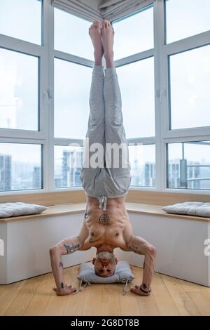 Gray-haired man in a white tshirt doing a headstand Stock Photo