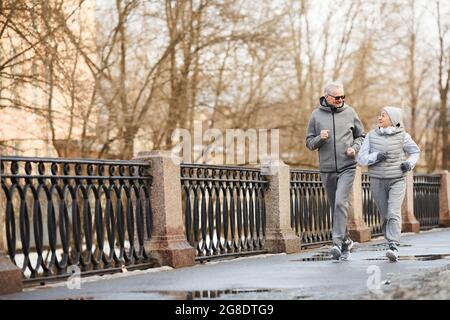 Full length wide angle view at active senior couple running outdoors in winter