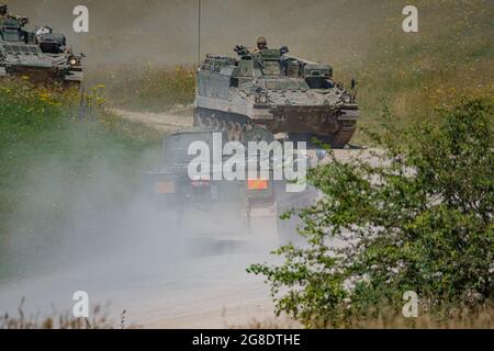 two British army Warrior FV512 Mechanised Recovery Vehicle tanks and an FV432 Bulldogon exercise kicking up clouds of dust on Salisbury Plain Stock Photo