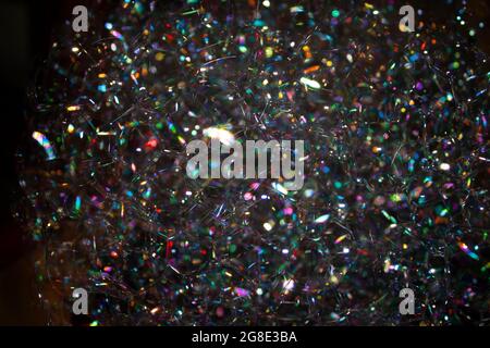 background photo of a cap of soap bubbles close-up in the dark, with glare of different colors of the rainbow Stock Photo