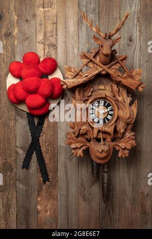 Original Black Forest cuckoo clock and Bollen hat in front of rustic wooden wall, Germany Stock Photo