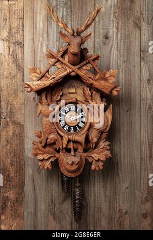 Original Black Forest cuckoo clock in front of rustic wooden wall, Germany Stock Photo