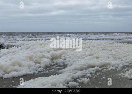 Area of shore covered in very heavy sea foam, high, rough seas, horizontal aspect Stock Photo