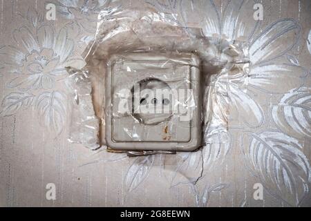 Close-up of an old broken electrical outlet sealed with transparent tape. Stock Photo