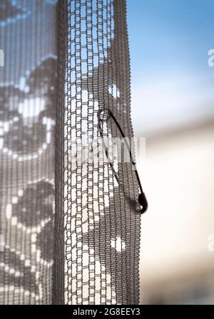 Close-up of a lone pin hanging on the curtain. Stock Photo