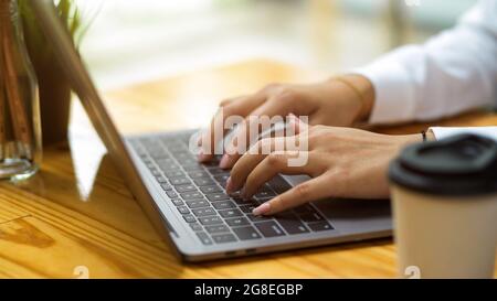 Cropped shot of college student doing work assignment via smart laptop at co-working space, female using laptop Stock Photo