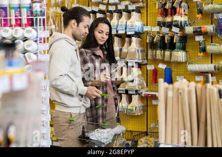 Young couple choosing painting brush in large household department Stock Photo