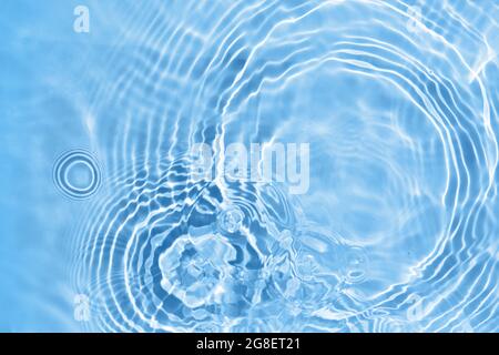 Blurred transparent blue colored clear water surface texture. Water waves in sunlight. Stock Photo