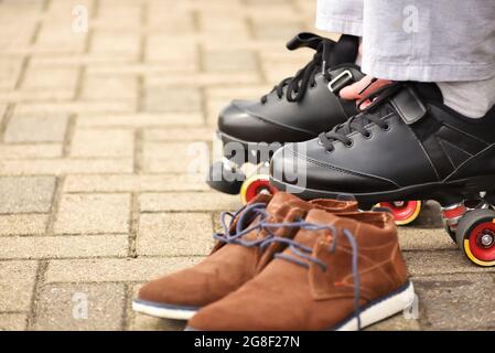 Man putting on roller skates. Changing casual shoes to roller skates before ride from office to home. Stock Photo