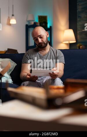 Anxious frustrated depressed young man reading letter, payment notification, bad financial report, renter problem, bank notice. Shocked, worried annoyed tenant by warning document for unpaid bills Stock Photo