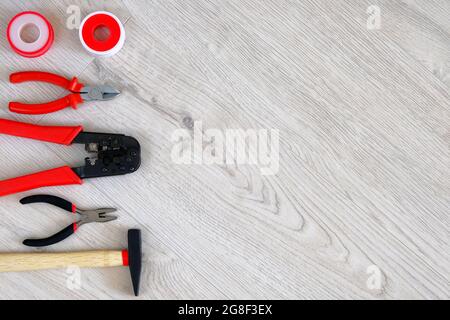 Flat lay of tools, parts, hammer and pliers on white wooden background, close up. Repair in home or apartment with special tools. Copy space. Stock Photo