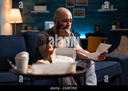 Desperate frustrated stressed young man reading letter, payment debt notification, bad financial report, eviction renter notice. Anxious, worried tenant by warning document for unpaid bank bills Stock Photo