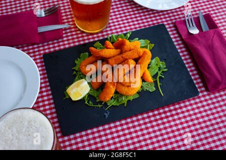 Sepia in a batter of tempera flour with lemon and arugula Stock Photo ...