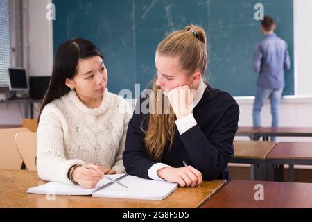 Tired female students during writing notes in classroom Stock Photo