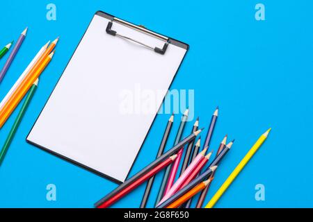 Clipboard and office supplies on blue background. Top view. Space for text Stock Photo