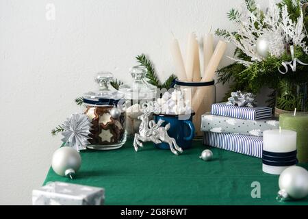 Festive decorated Christmas or New Year's table, thuja and decorative spruce branches, candles and Christmas balls, cookies in a jar Stock Photo
