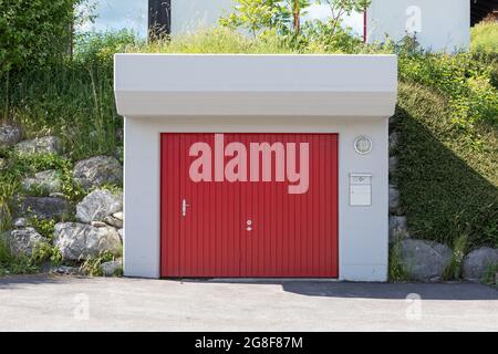 concrete garage in the garden with red gate Stock Photo