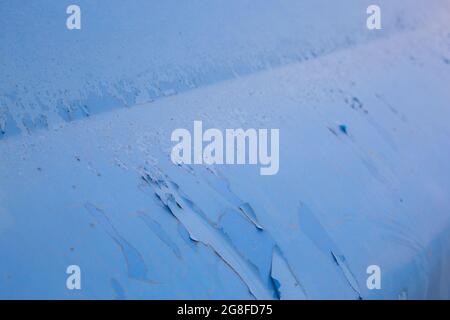 peeling off old blue paint on vehicle - close-up with selective focus. Stock Photo