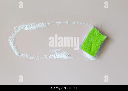 Sponge on soapy foam background. Washing dishes concept. Flat lay, Top view. Stock Photo