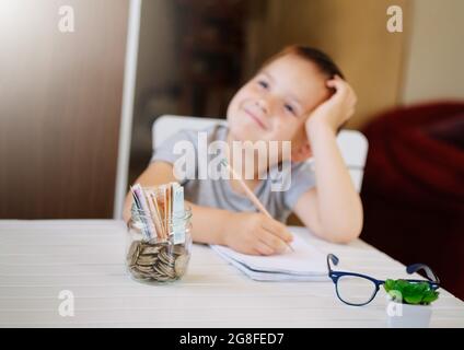 Kid Save money and dreaming about new toys, making a wish list, account banking for finance concept. Turkish lira coins in glass jar and banknotes Stock Photo