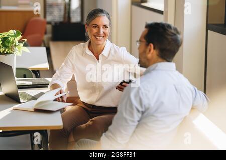 business partners sitting at desk and discussing business strategy. Entrepreneurs doing discussion on new ventures in office. Stock Photo