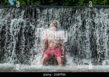 A man cools off in the water at Warleigh Weir on the River Avon near Bath in Somerset as temperatures soar across the United Kingdom Stock Photo