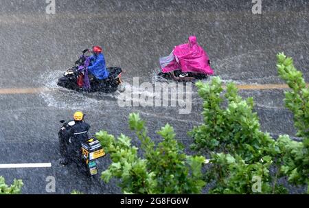 Zhengzhou, Henan, China. 20th July 2021.  People ride on a waterlogged road in Zhengzhou, capital of central China's Henan Province, July 20, 2021. More than 144,660 residents have been affected by torrential rains in central China's Henan Province since July 16, and 10,152 have been relocated to safe places, the provincial flood control and drought relief headquarters said Tuesday. Credit: Xinhua/Alamy Live News