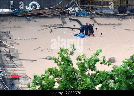 Zhengzhou, Henan, China. 20th July 2021.  Staff members drain away water at a construction site in Zhengzhou, capital of central China's Henan Province, July 20, 2021. More than 144,660 residents have been affected by torrential rains in central China's Henan Province since July 16, and 10,152 have been relocated to safe places, the provincial flood control and drought relief headquarters said Tuesday. Credit: Xinhua/Alamy Live News