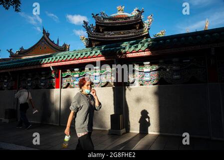 July 19, 2021, Taipei, Taiwan: An lady wearing a face mask walks past a nearby temple in Wanhua..Local authorities of the two cities have made mask wearing in outdoor areas. (Credit Image: © Shih Hsun Chao/SOPA Images via ZUMA Press Wire) Stock Photo