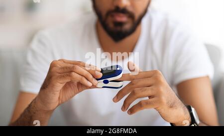 Unrecognizable man using pulse oximeter at home Stock Photo