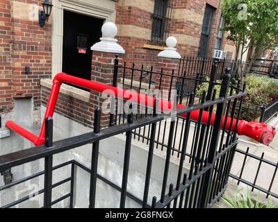 Bright red standpipe connected to the London Terrace apartment complex in Chelsea in New York on Wednesday, July 14, 2021.  A standpipe is a dry line that the fire department connects to deliver water to upper, or in this case below ground, floors.  (© Frances M. Roberts) Stock Photo