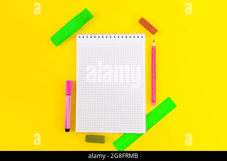 Back to school. Education. Notebook cell for notes, markers, crayons, pencil, ruler on yellow background. Flat lay. Copy space Stock Photo