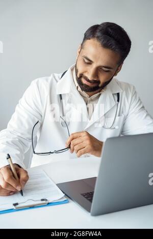 Vertical portrait of doctor writing in patient card during online consultation Stock Photo