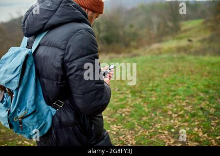 Traveler man with backpack with compass in hand on a background of mountains river of nature, Travel concept, camping trip, GPS, orienteering, navigat Stock Photo