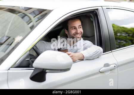 Happy businessman driving car while drinking coffee takeaway, good morning and road to office Stock Photo