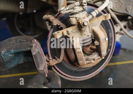 An auto mechanic removed a completely worn out brake pad, a concept on the timely replacement of car parts Stock Photo