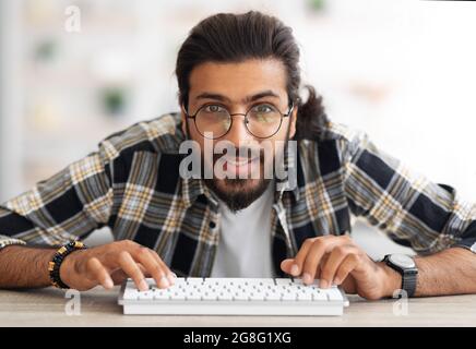 Young middle-eastern man programmer sitting at worktable Stock Photo