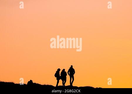 People watch the sunset on top of Cavehill mountain, overlooking Belfast in Northern Ireland, on the longest day of the year during Summer Solstice. Stock Photo