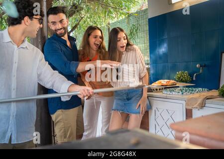 Group of people having fun cooking pizza outdoors. Friends gathering for a pizza party. Stock Photo