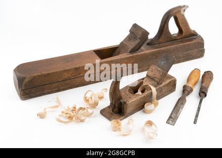 High angle studio shot of two vintage wood planers and chisels of different sizes, isolated on white background. Old carpenter tools with wood worm Stock Photo