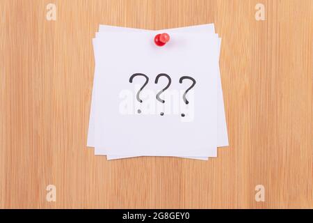 White Sticky Notes with Three Question Marks Pinned to the Wooden Message Board. To Do List Reminder in the Office. Memo Note at Work Stock Photo