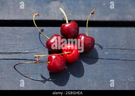 five red cherries on a wooden table Stock Photo