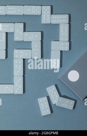 Light Blue wood domino pieces on light blue background. Leisure games concept. Stock Photo