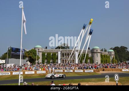 Stirling Moss driving Mercedes Benz W196 historic car at the Goodwood Festival of Speed event, passing Goodwood House and the Porsche central feature Stock Photo
