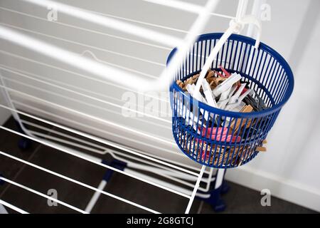 Empty laundry drying rack with clothespins in blue basket, clothing rack dryer clean new design indoors Stock Photo