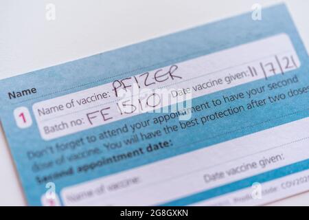 An NHS UK COVID-19 vaccination record card showing that the first PFIZER vaccine has been given, England, UK Stock Photo