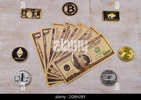 Golden dollar bills surrounded by cryptocurrency gold and silver coins Bitcoin ethereum dash On white wood surface Stock Photo