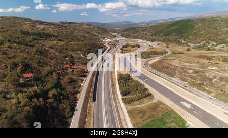 Road curves through hilly landscape. Sky and clouds. Sunny. Stock Photo