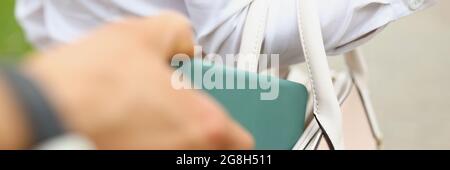 A man steals a wallet from a womans bag close up Stock Photo